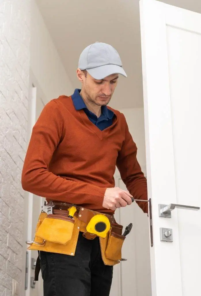 Skilled technician repairs door lock in modern home during daylight hours Skilled technician repairs door lock in modern home during daylight hours