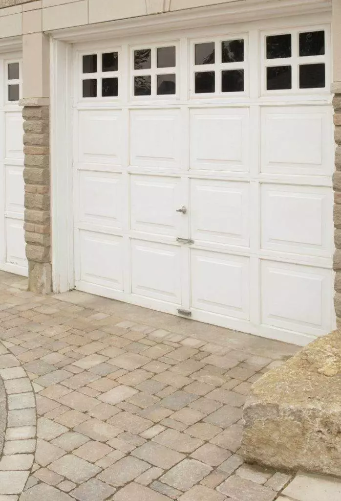 Elegant white garage door with stone accents and paved driveway in a modern residential setting