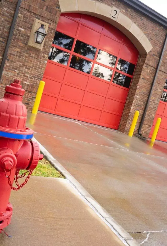 Fire hydrant in front of fire station with bright red doors on a rainy day