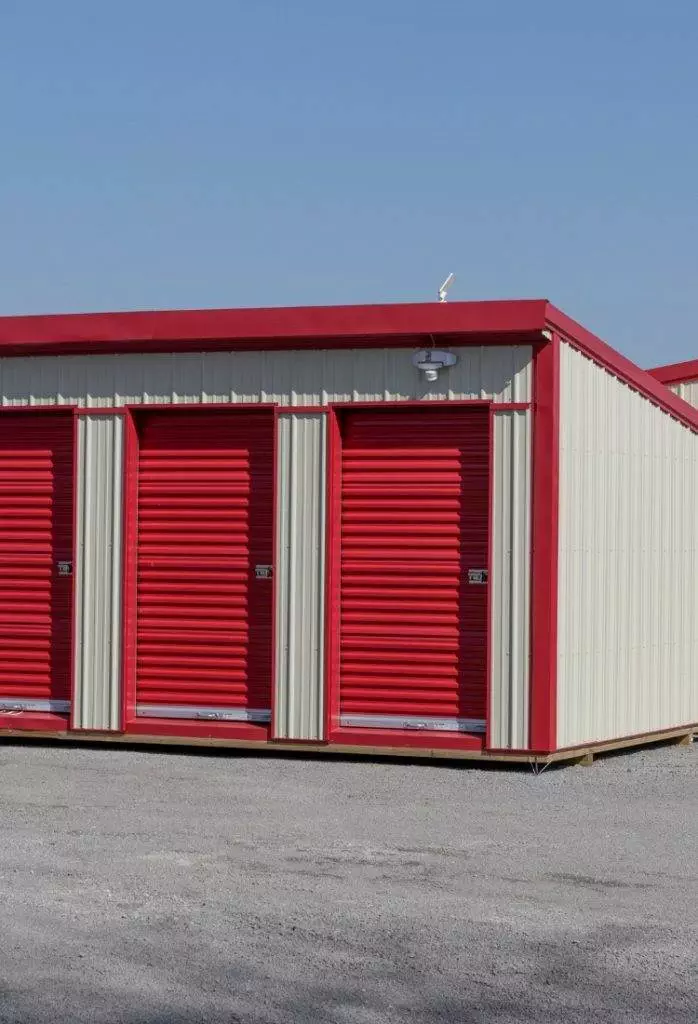 Storage facility with red and white units under a clear blue sky in a suburban area