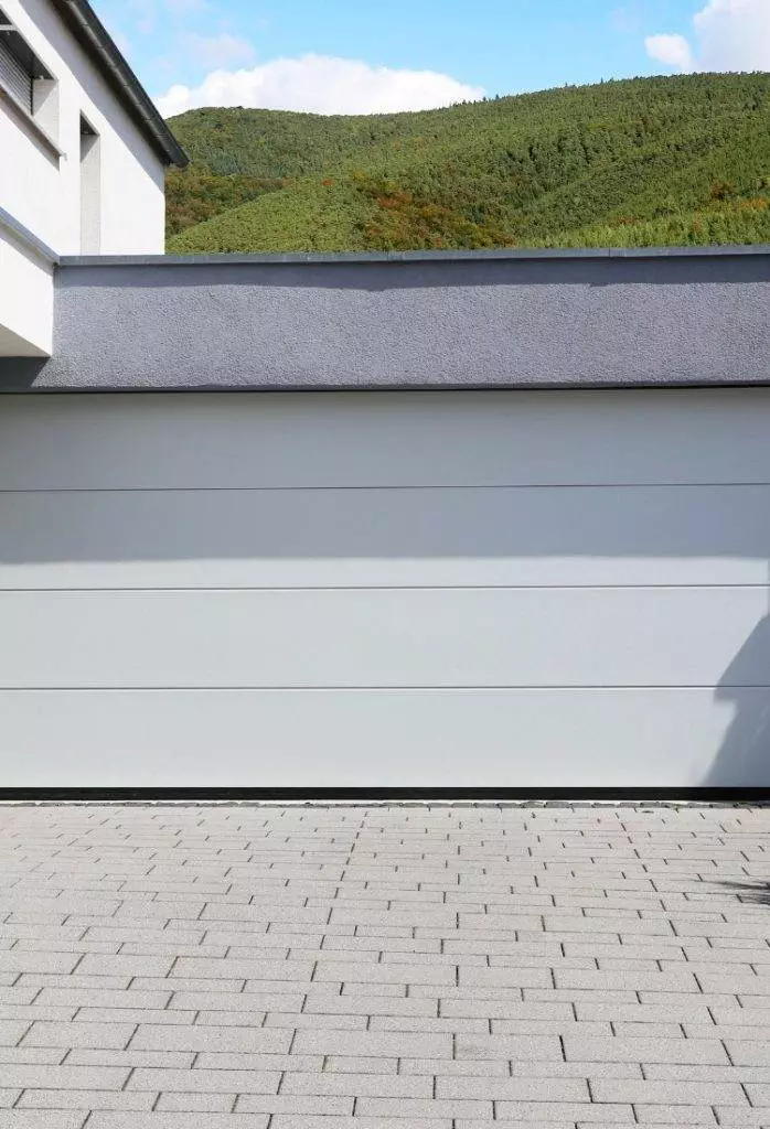 Modern garage design with smooth grey surface and green hillside in the background on a sunny day