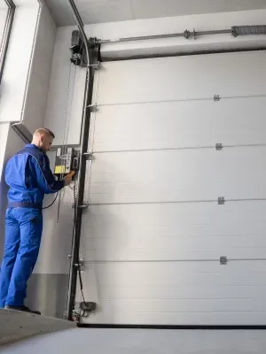 Custom garage door technician adjusting controls while working on design in modern garage Custom garage door technician adjusting controls while working on design in modern garage