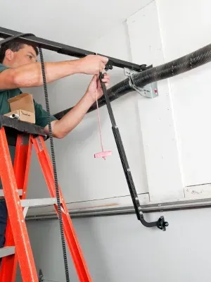 Garage door cable replacement process in a residential garage during daylight hours Garage door cable replacement process in a residential garage during daylight hours